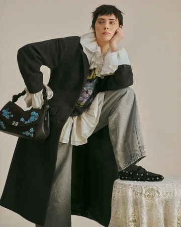 Model wearing a grey coat and white lace shirt from the Fall/Winter 2026 collection